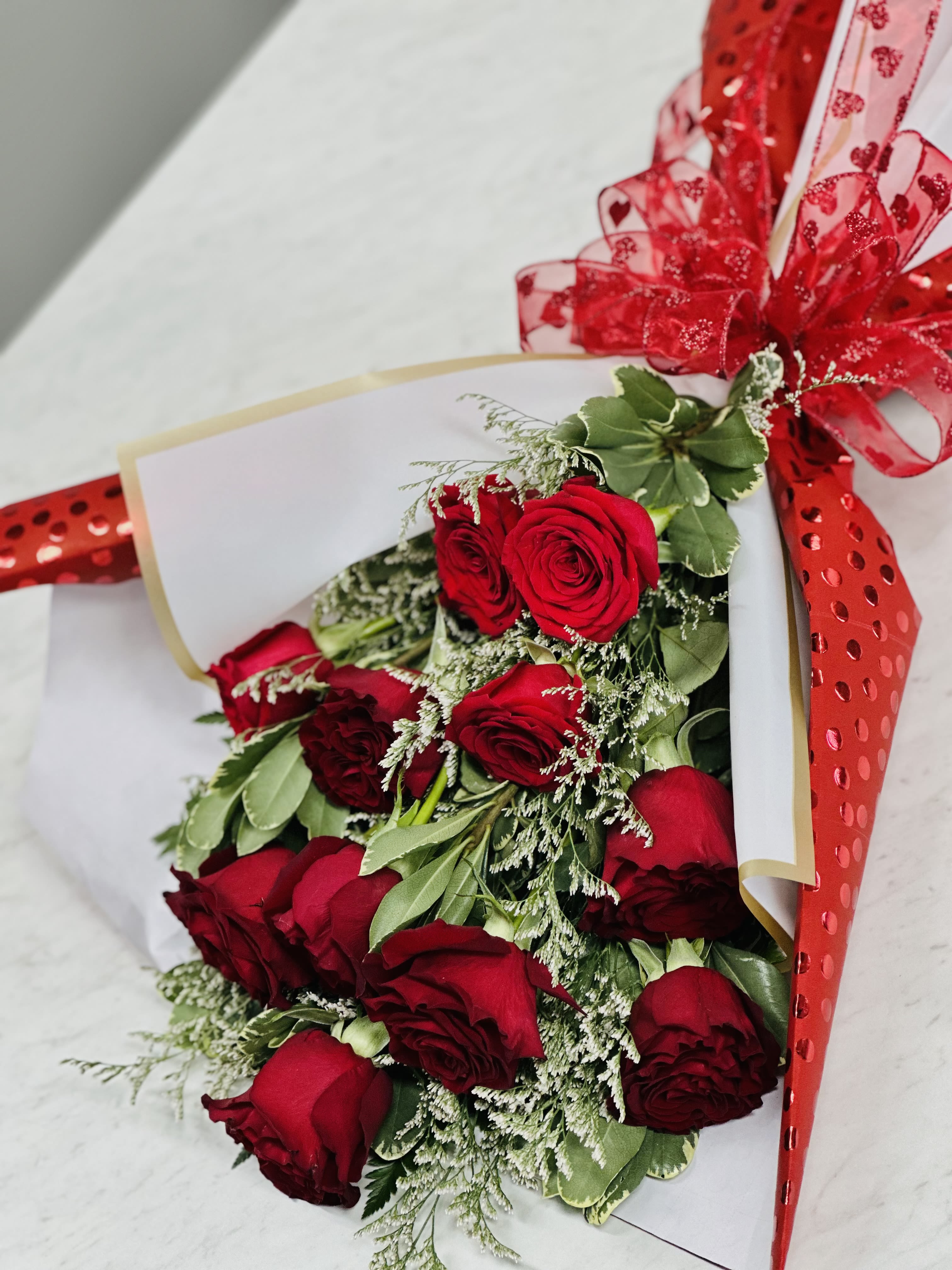 Bouquet of red roses wrapped in white paper with a red ribbon