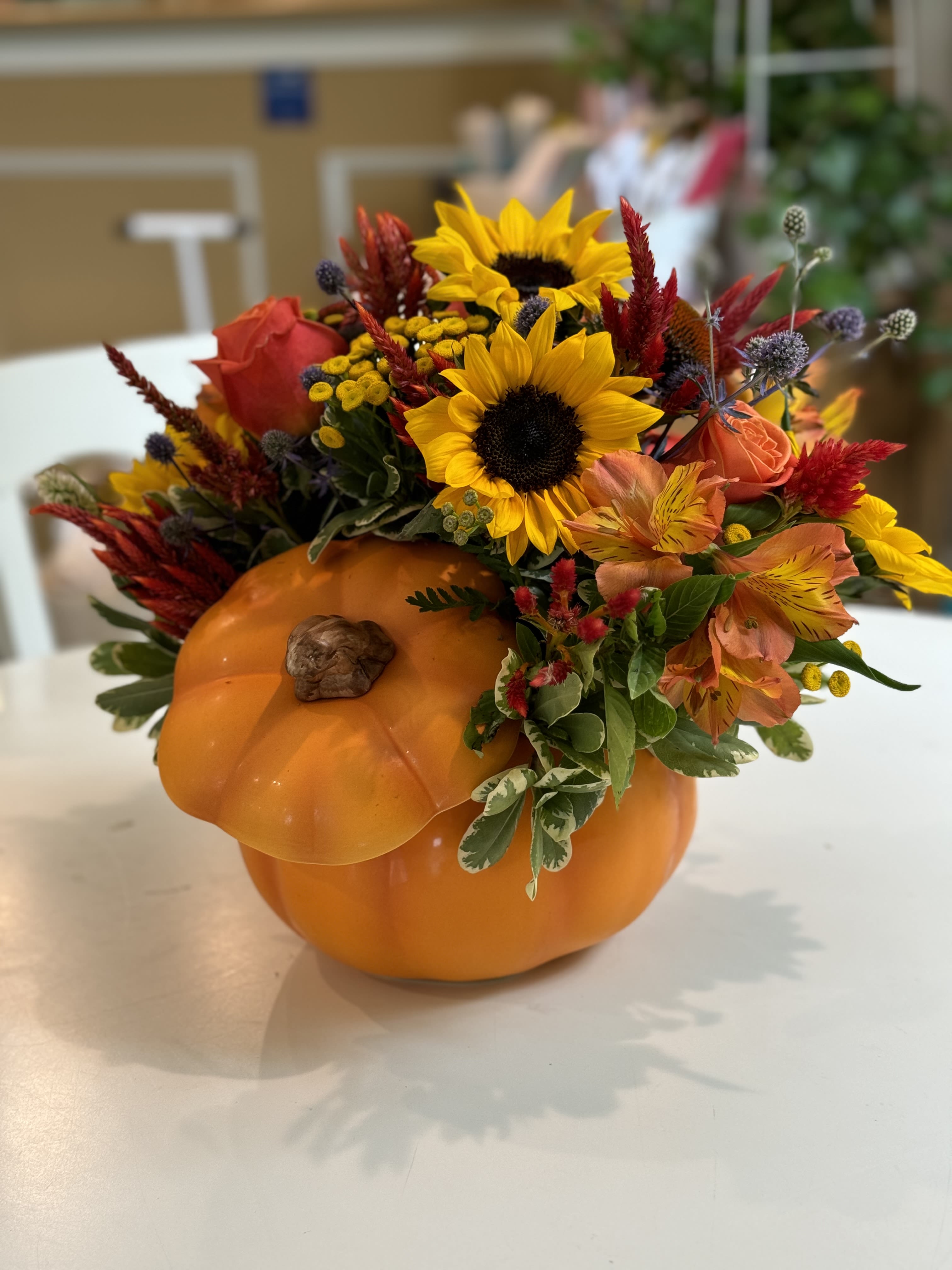 Fall floral arrangement in a pumpkin container with sunflowers and orange blooms