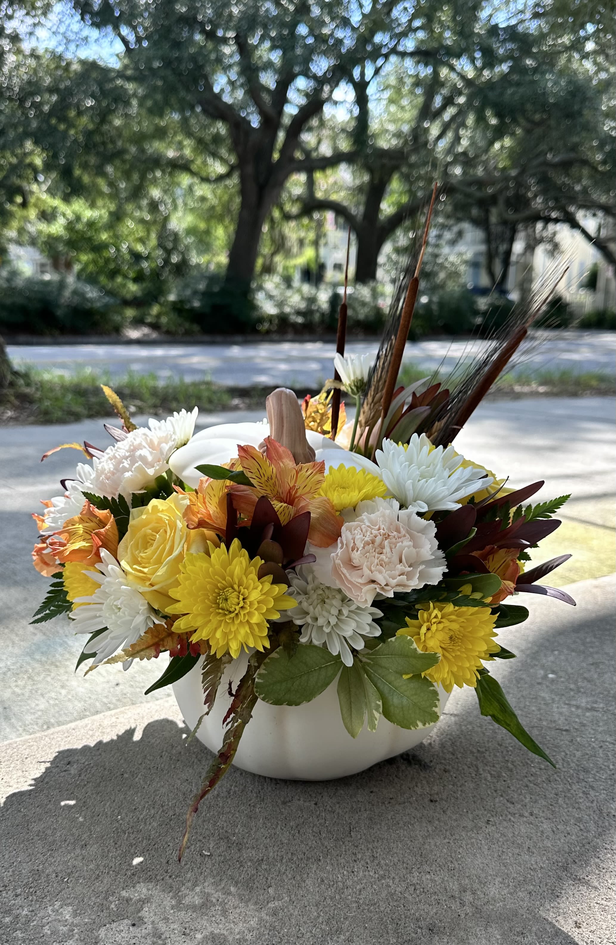 Autumn floral arrangement in a white pumpkin vase with yellow, white, and peach blooms