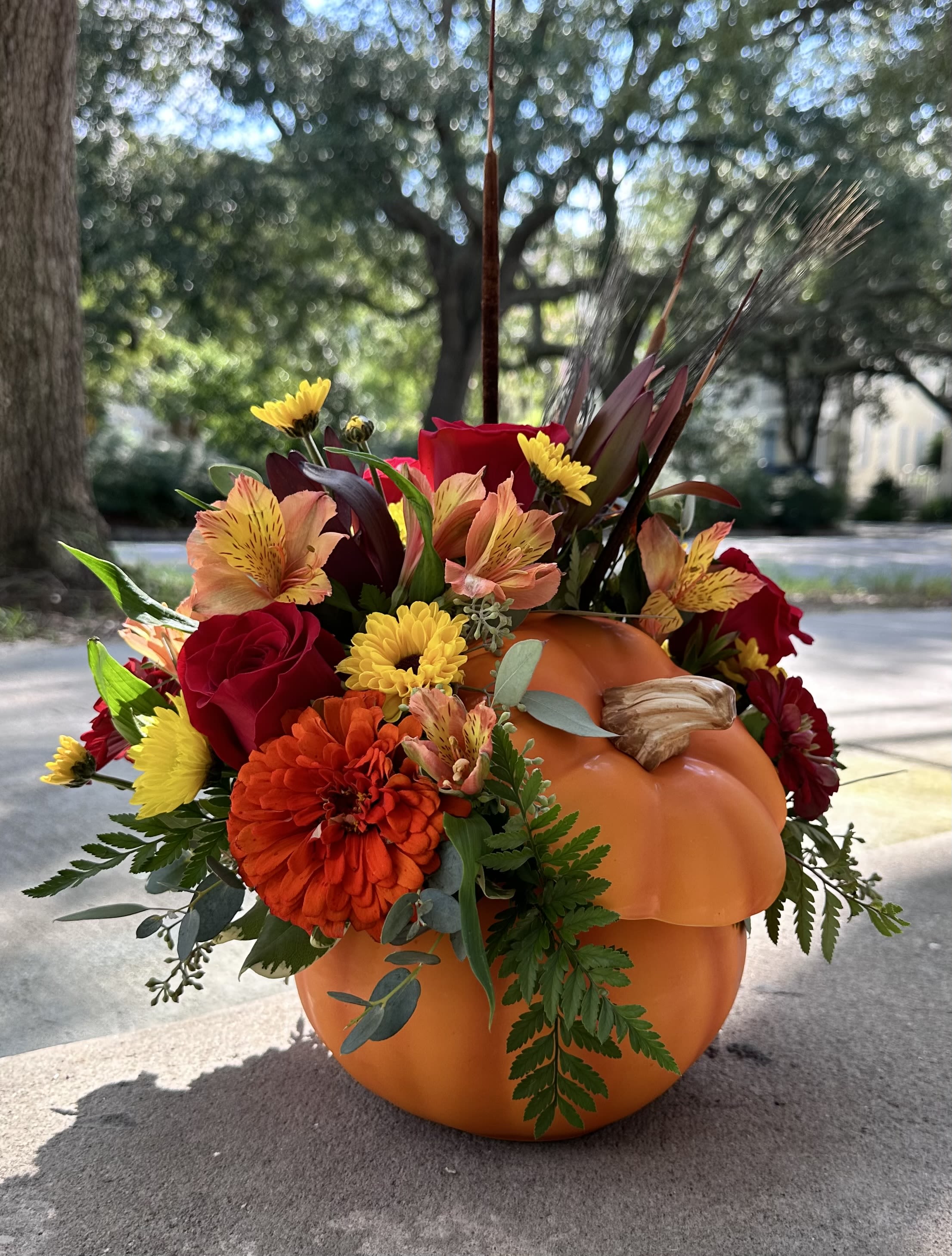 Fall floral arrangement in a carved pumpkin with red, orange, and yellow blooms