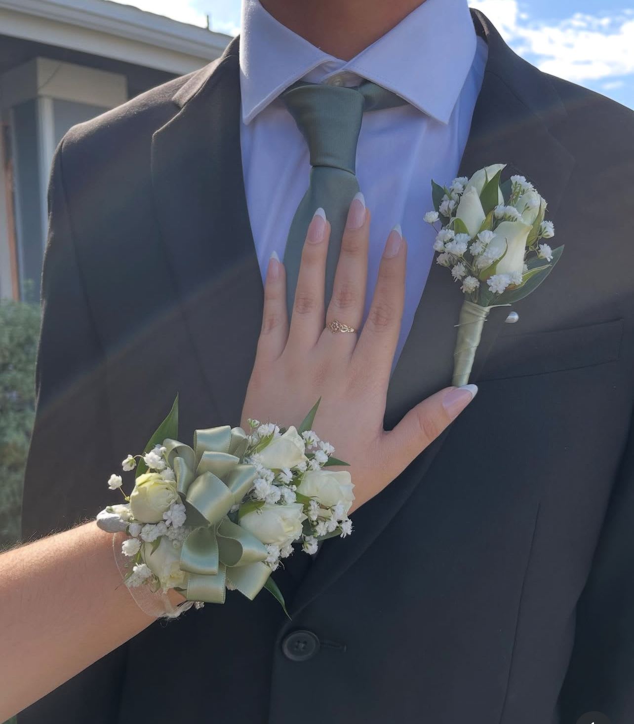 White boutonniere and wrist corsage with pale green ribbon on formalwear