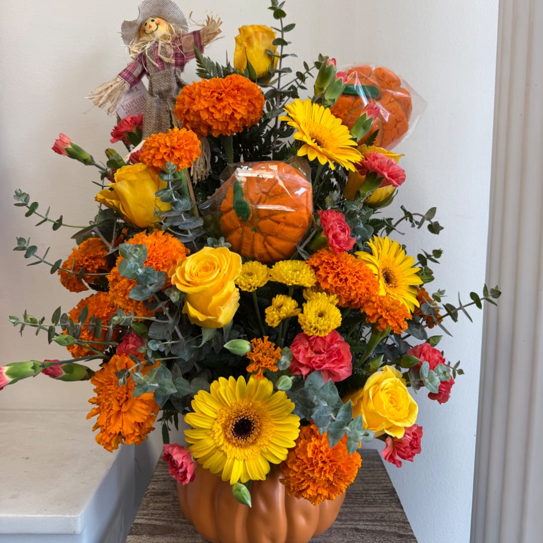 Pumpkin-themed bouquet with yellow roses, gerbera daisies, and orange marigolds in a pumpkin vase