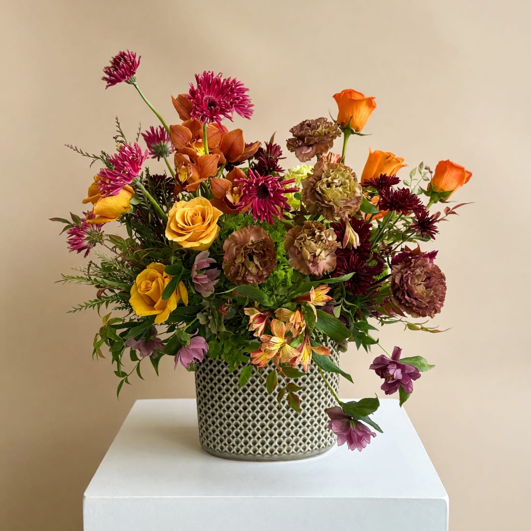 Mixed bouquet in a patterned metal vase with orange and purple blooms