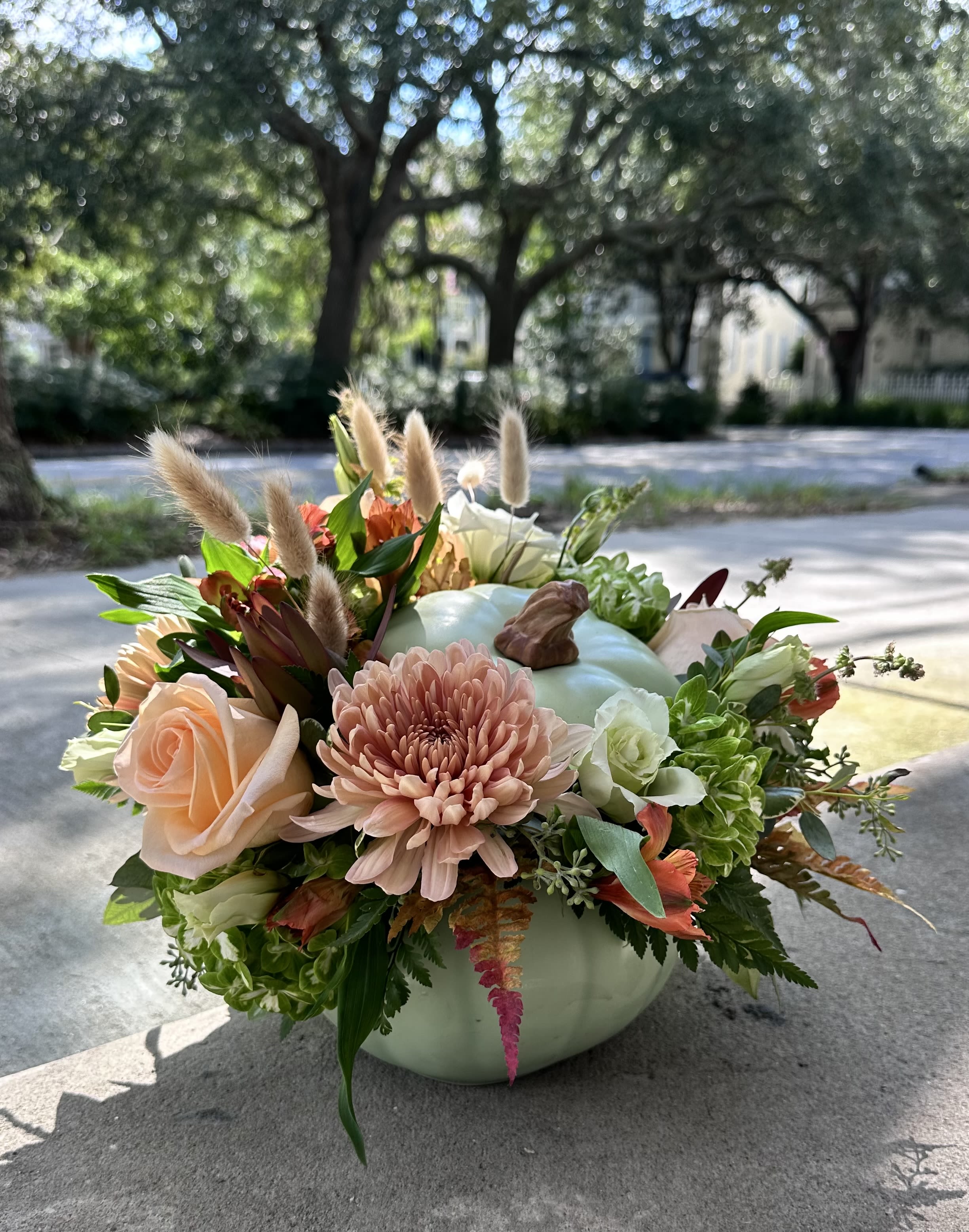 Pumpkin-shaped vase with peach and white flowers and dried grasses