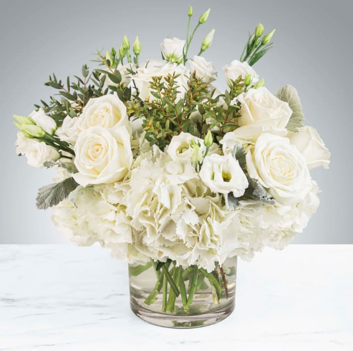 White roses and hydrangeas in a clear glass vase