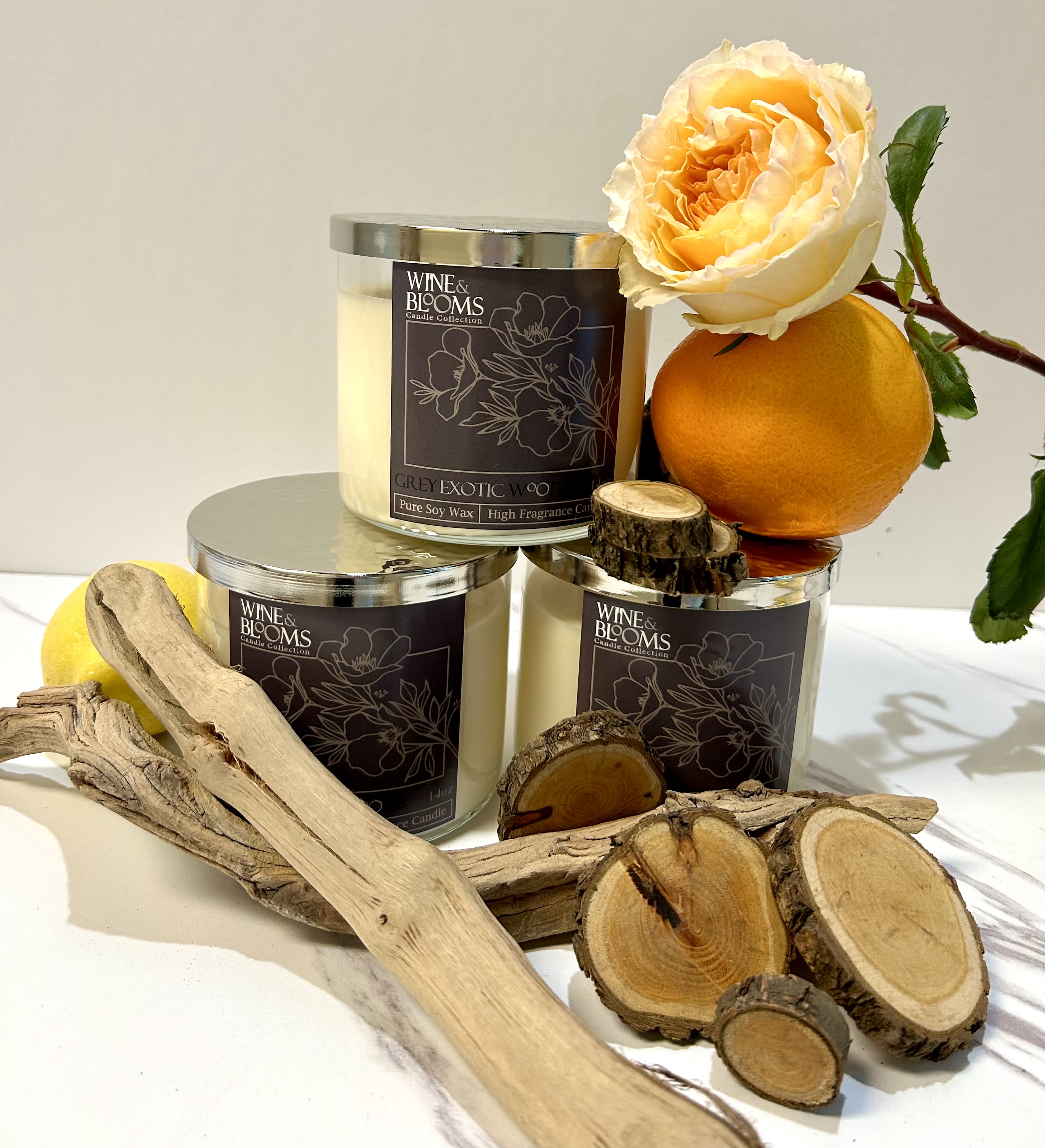 Three candles with an orange rose and citrus fruit accents