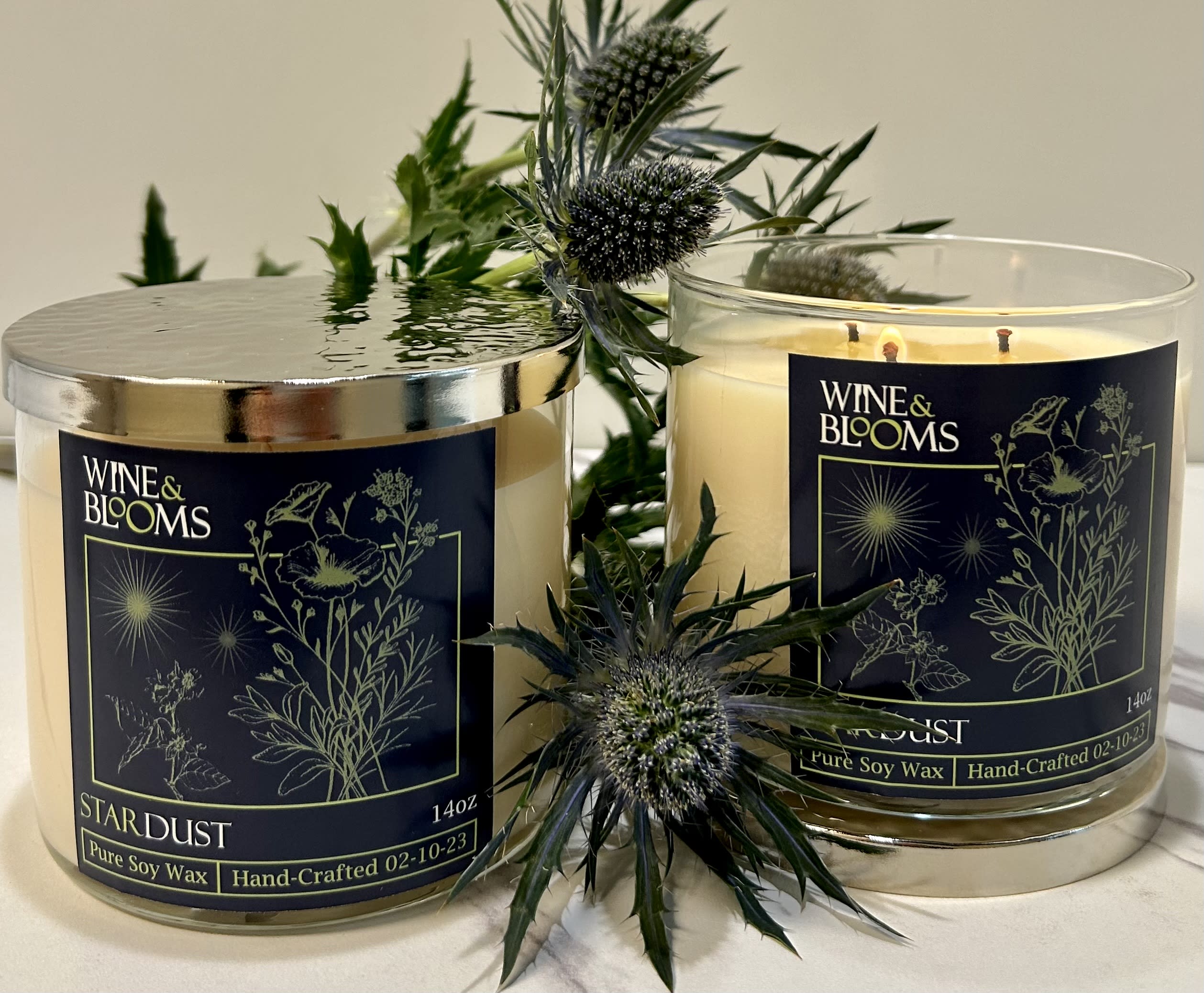 Two scented candles with floral labels and thistle-like stems