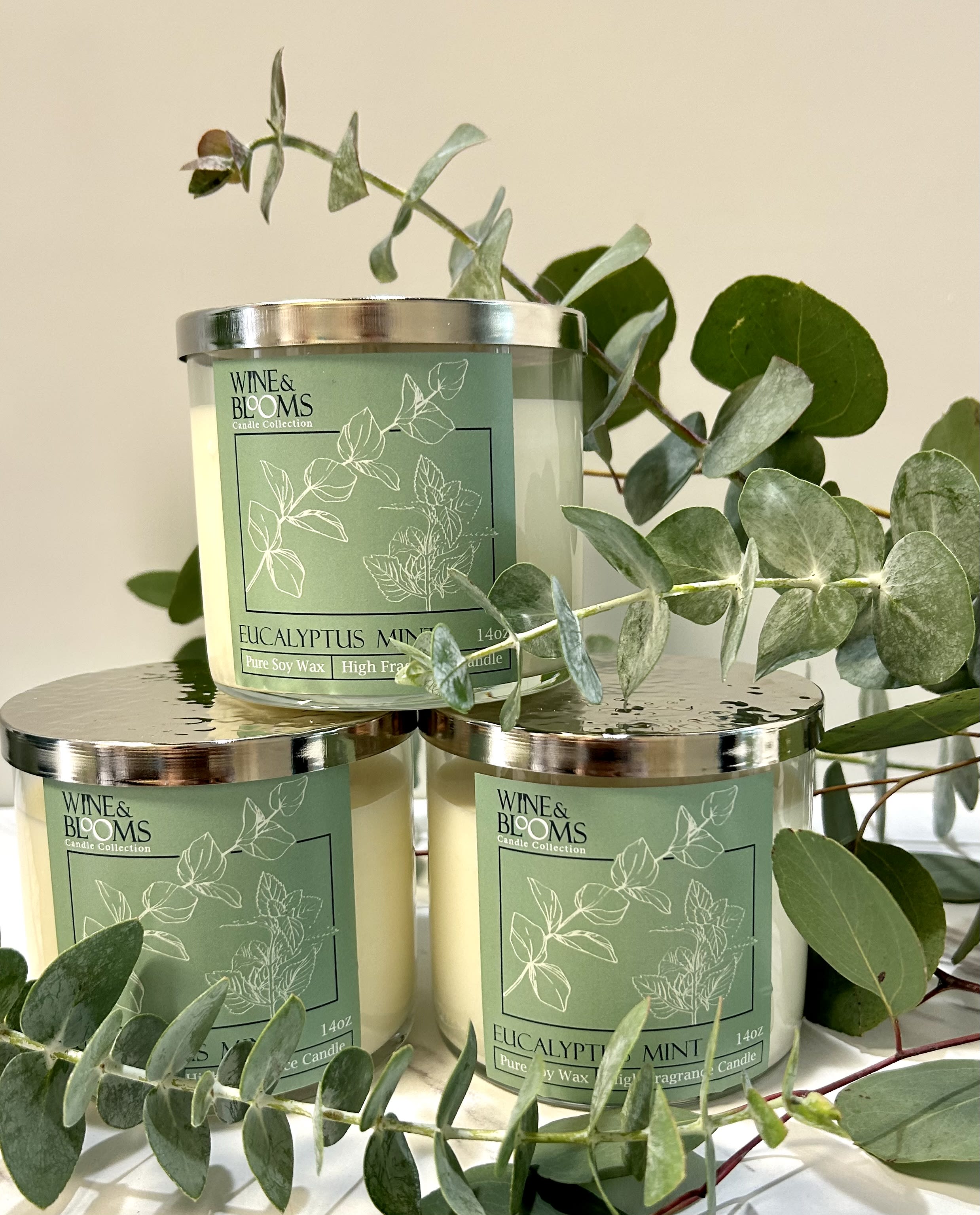 Three eucalyptus mint candles with eucalyptus branches