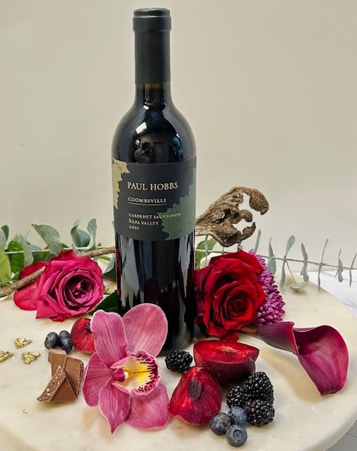 Wine bottle surrounded by roses, orchid petals, and berries
