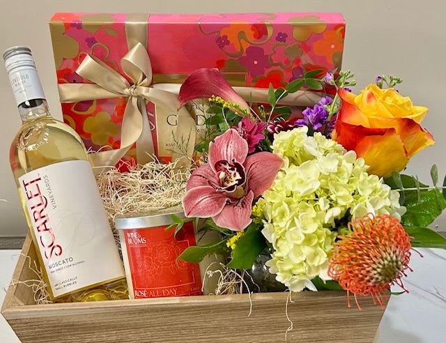 Gift basket with flowers, wine bottle, candle, and ribboned box