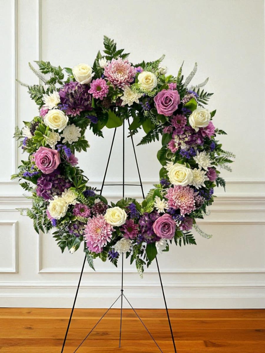 Floral wreath on a black stand with pink, white, and purple blooms