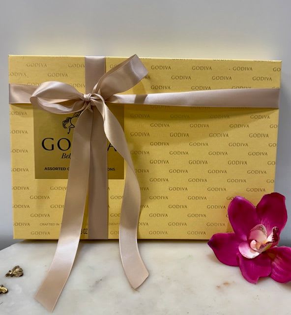 Gift box of Godiva chocolates tied with a satin ribbon and orchid bloom