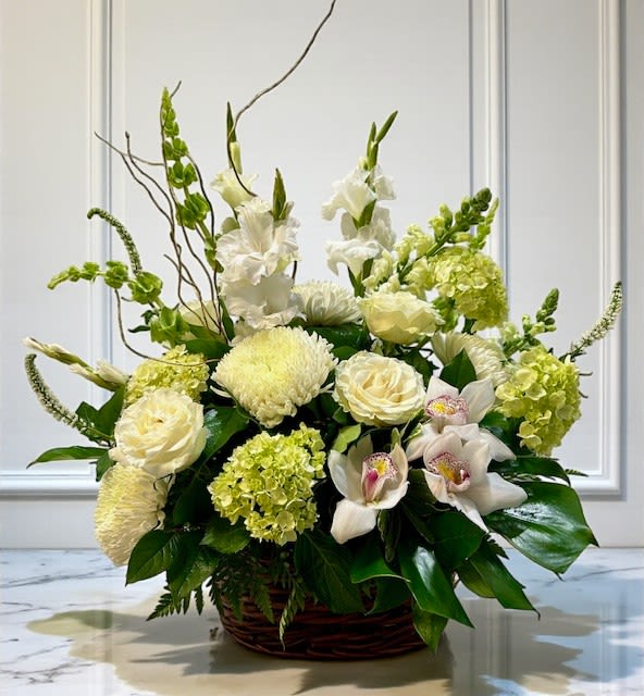 White and pale green floral arrangement in a wicker basket