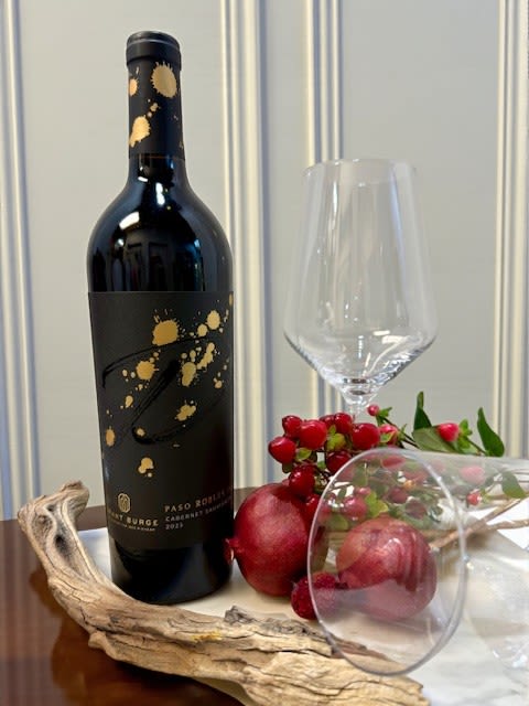 Wine bottle with a clear stemmed glass and red fruit accents