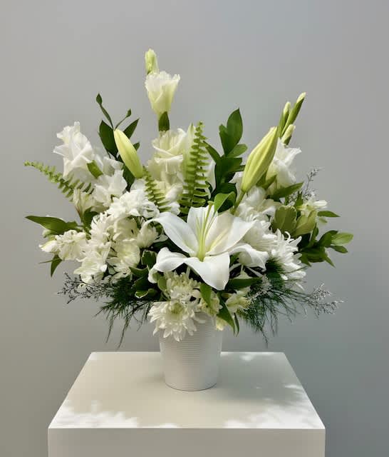 White lilies and chrysanthemums arranged in a white vase