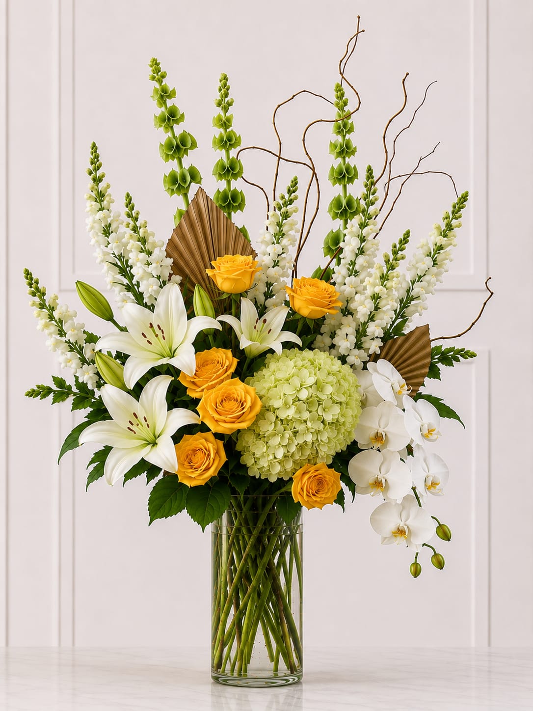 Tall bouquet of white lilies, yellow roses, and white orchids in a glass vase