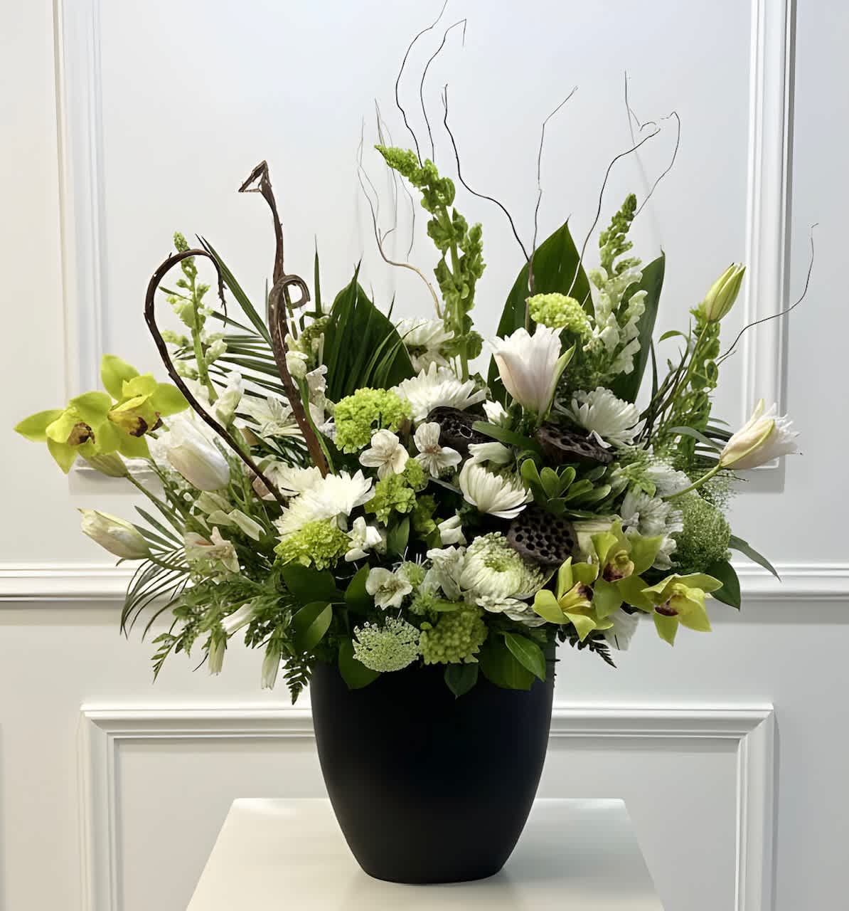 White and green floral arrangement in a black vase