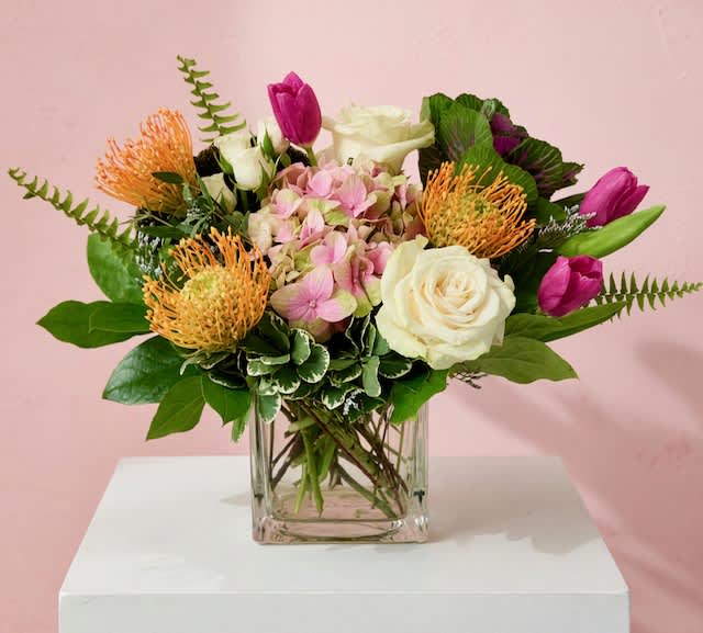 Mixed bouquet of pink, white, and orange flowers in a clear glass vase