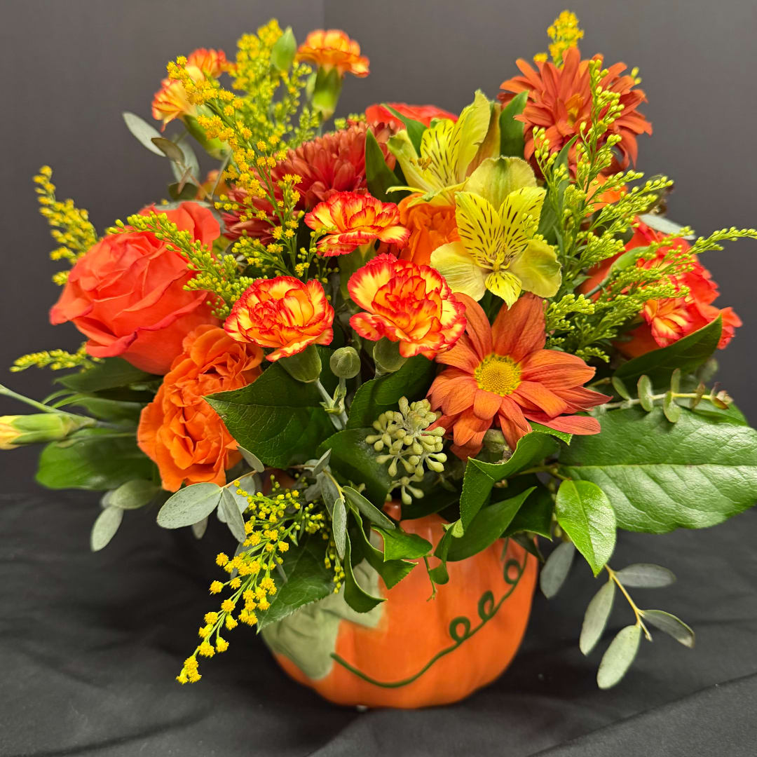 Orange and yellow mixed bouquet in a painted pumpkin container