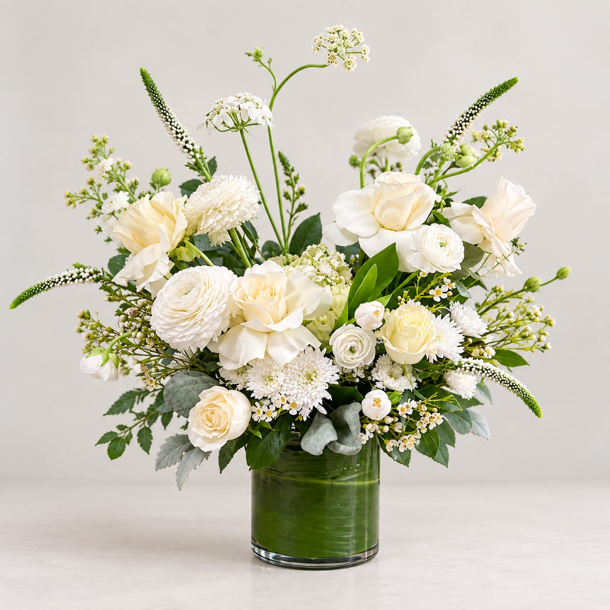 White floral arrangement in a green glass vase