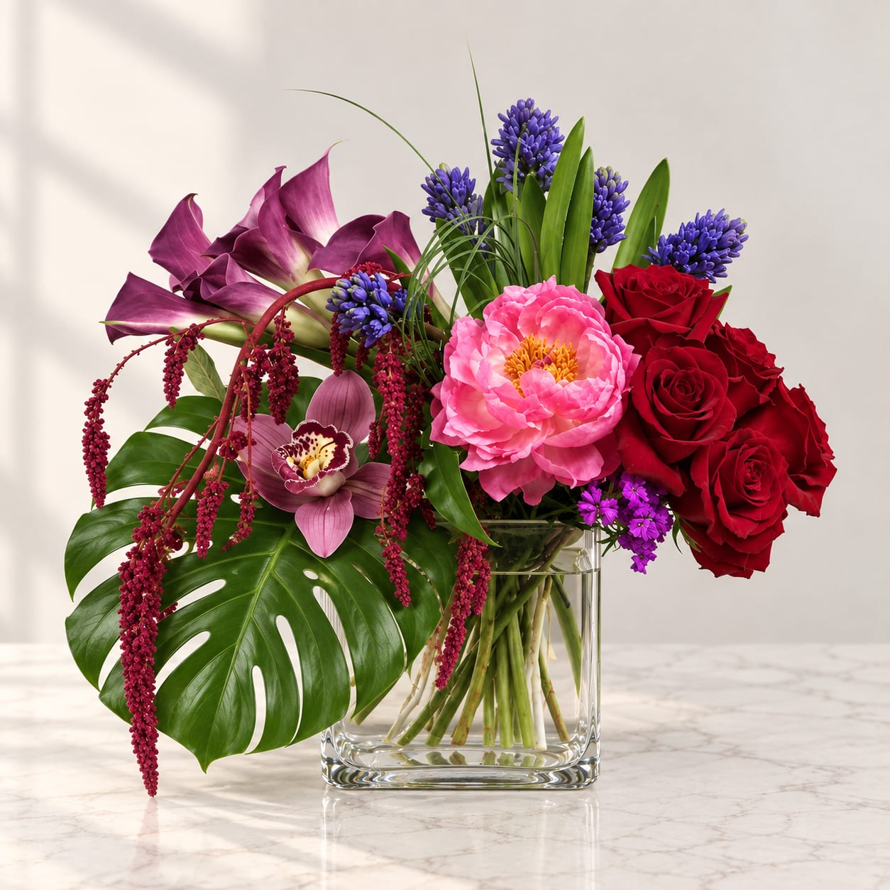 Mixed bouquet in a clear glass vase with red roses and pink blooms