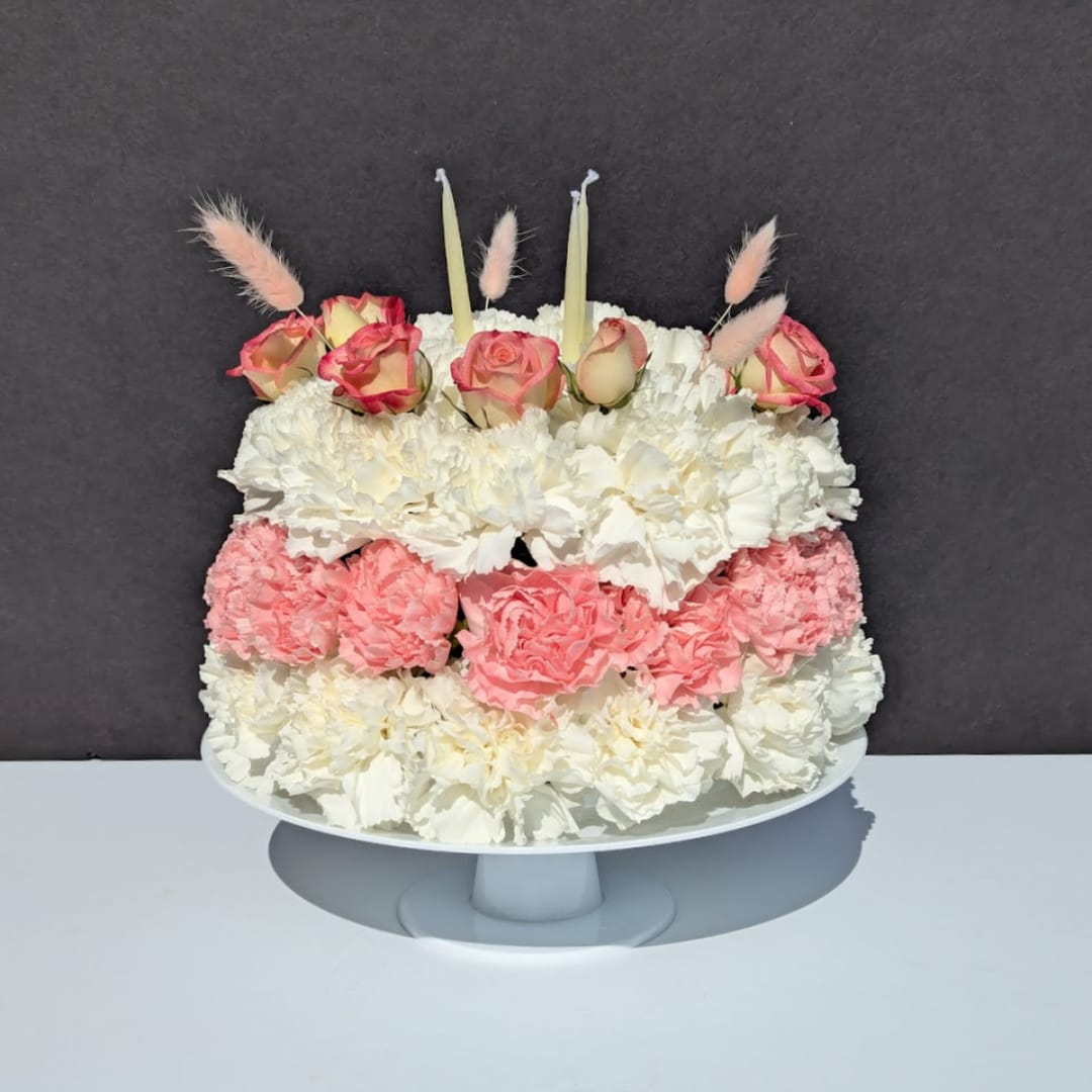 Pink and white floral cake on a white pedestal stand