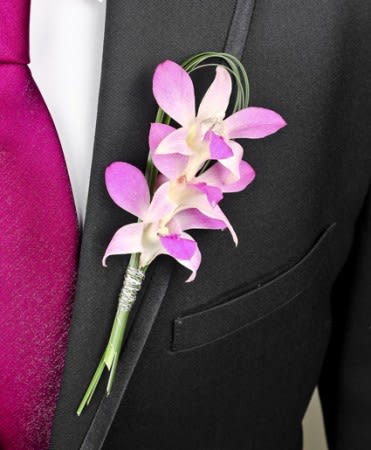 Pink orchid boutonniere pinned to a black suit jacket