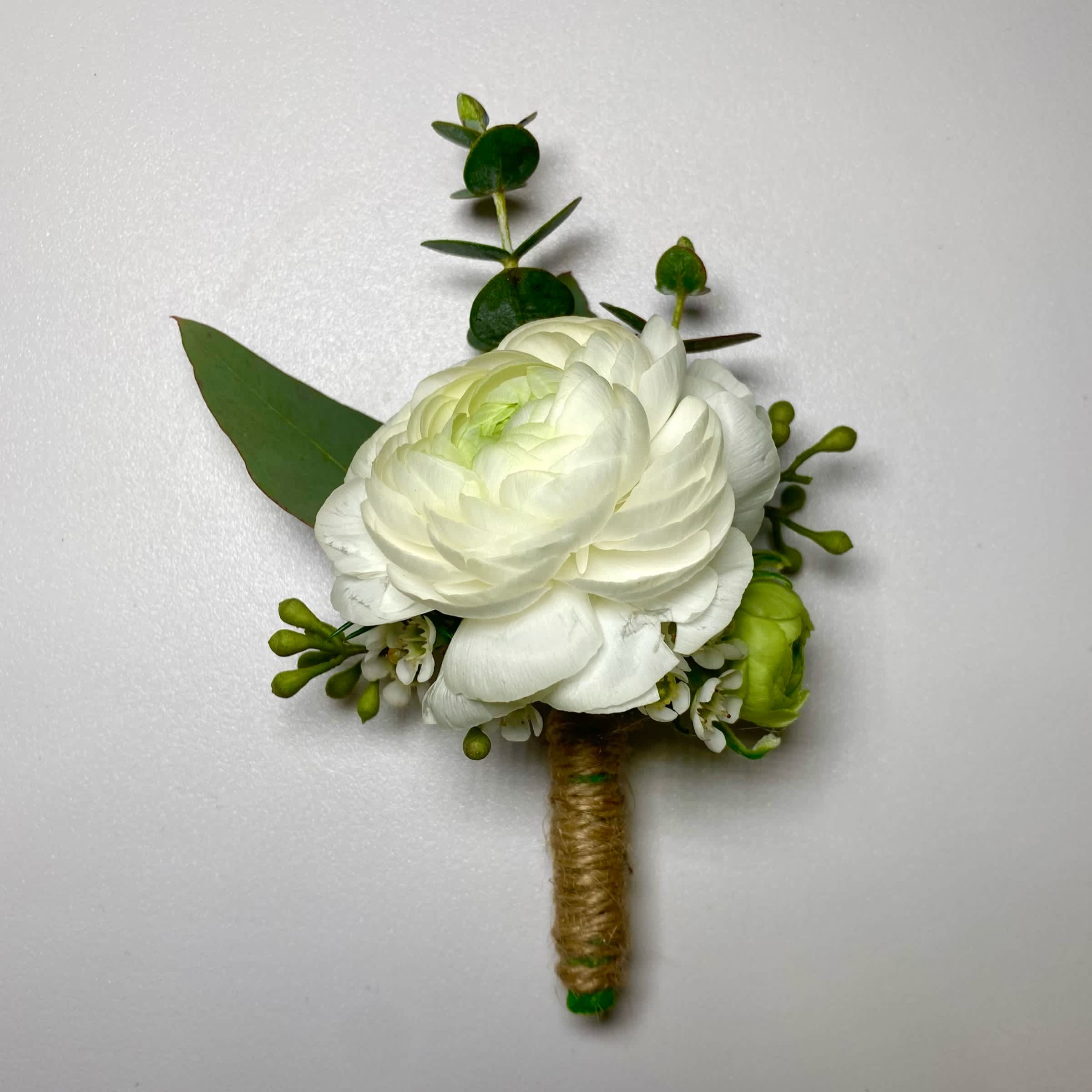 White floral boutonniere with green accents and wrapped stem