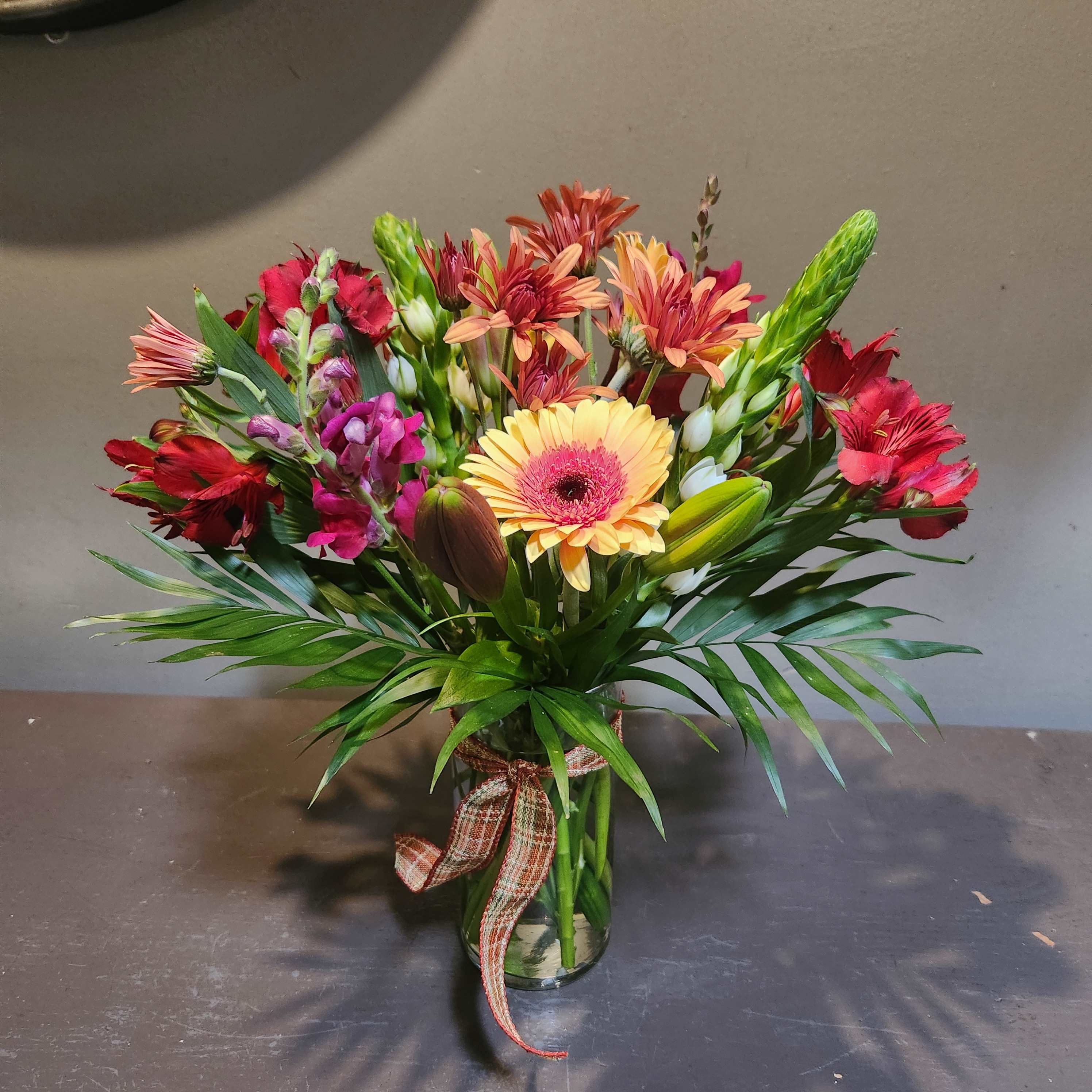 Mixed bouquet with gerbera daisies, alstroemeria, and snapdragons in a glass vase