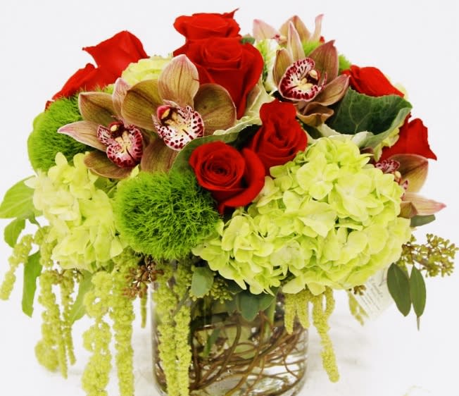Bouquet of red roses, green hydrangeas, and orchids in a glass vase