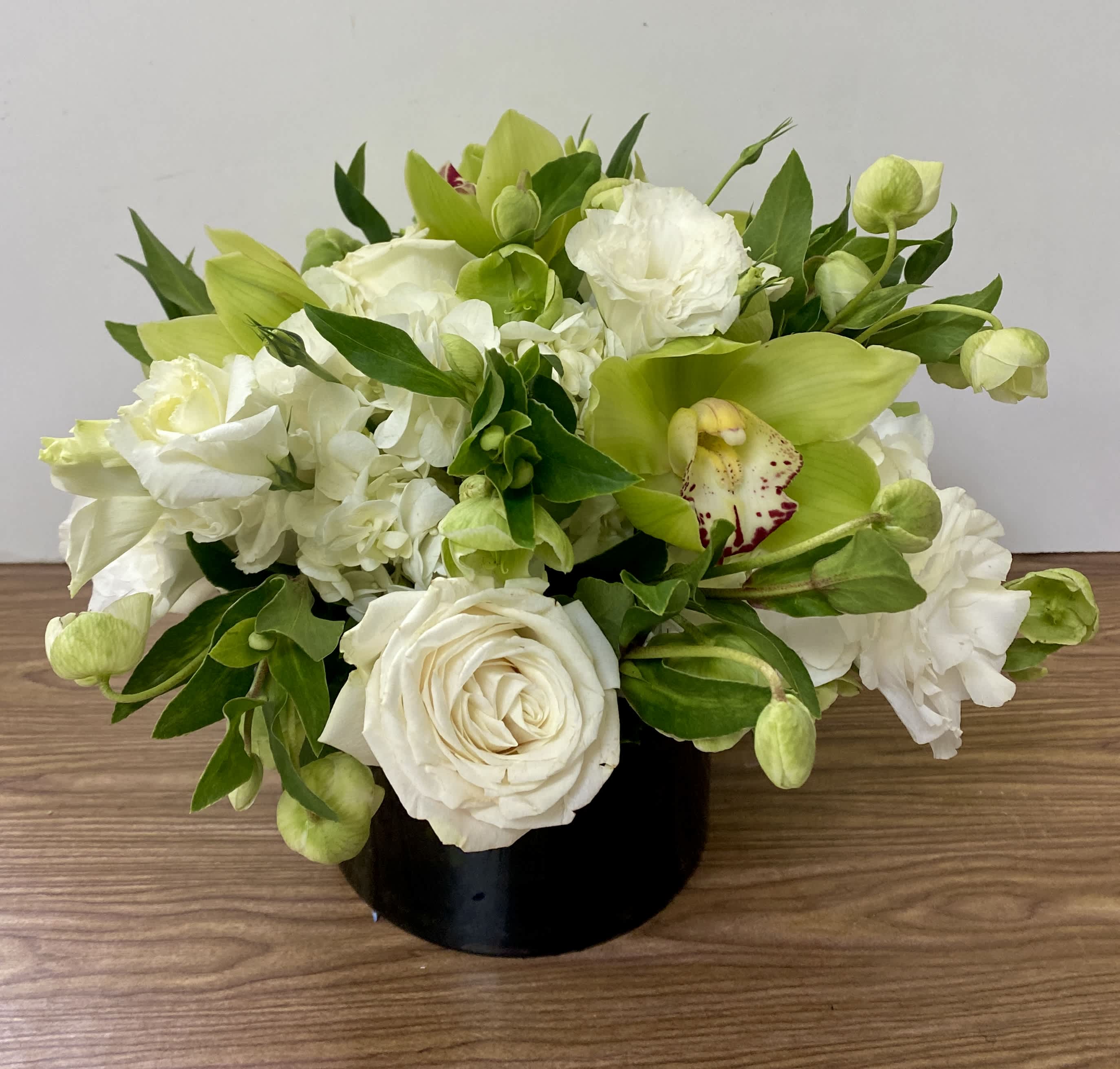 White and green floral arrangement in a black vase