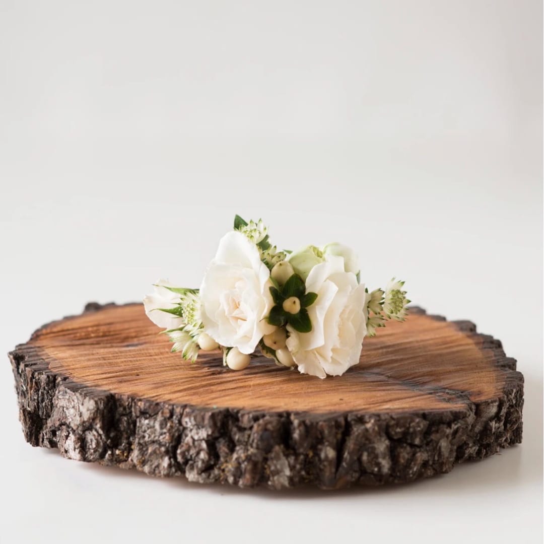Small white floral corsage on a wood slice