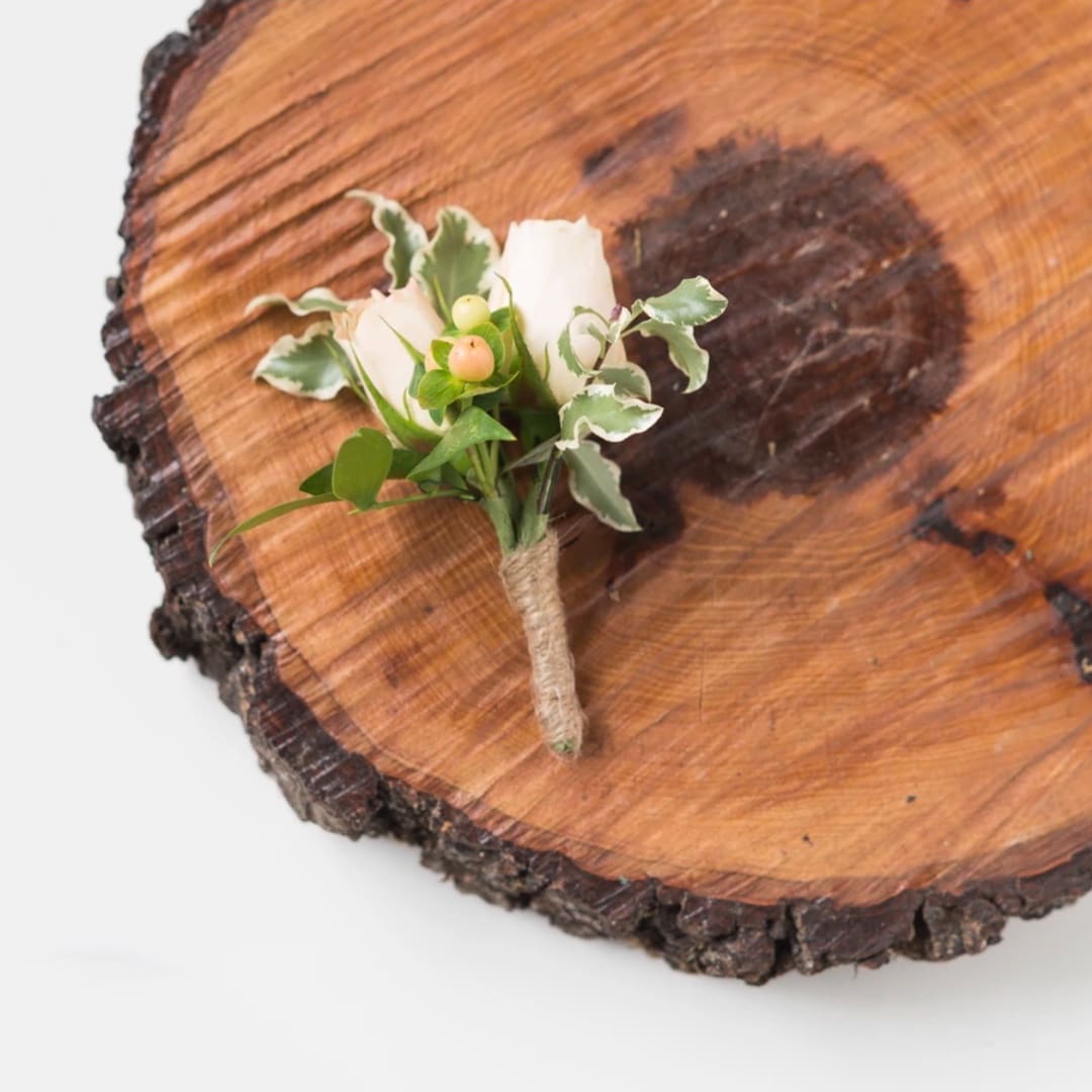 Small white boutonniere with berries on a wood slice