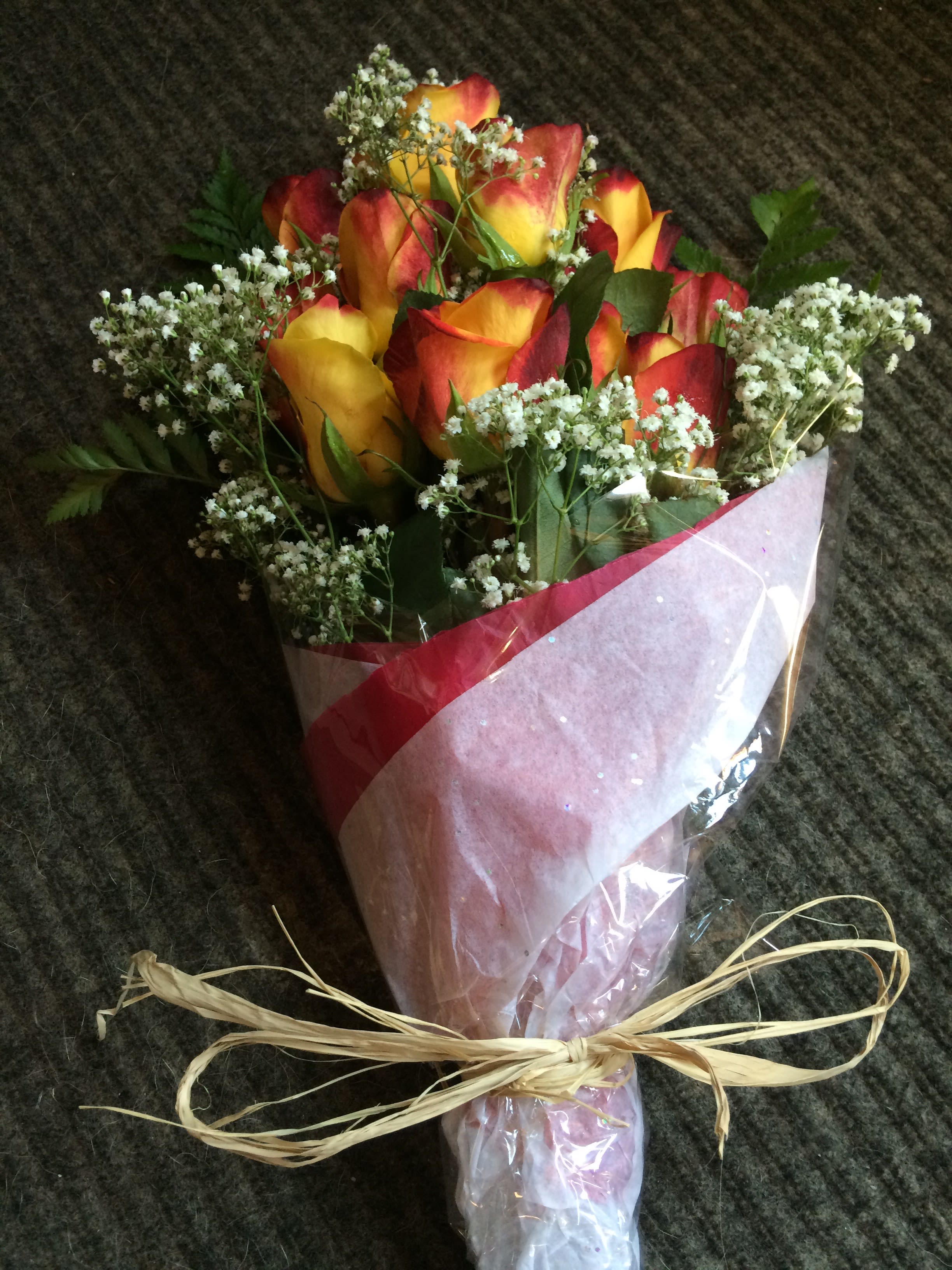 Bouquet of red and yellow roses wrapped in pink paper