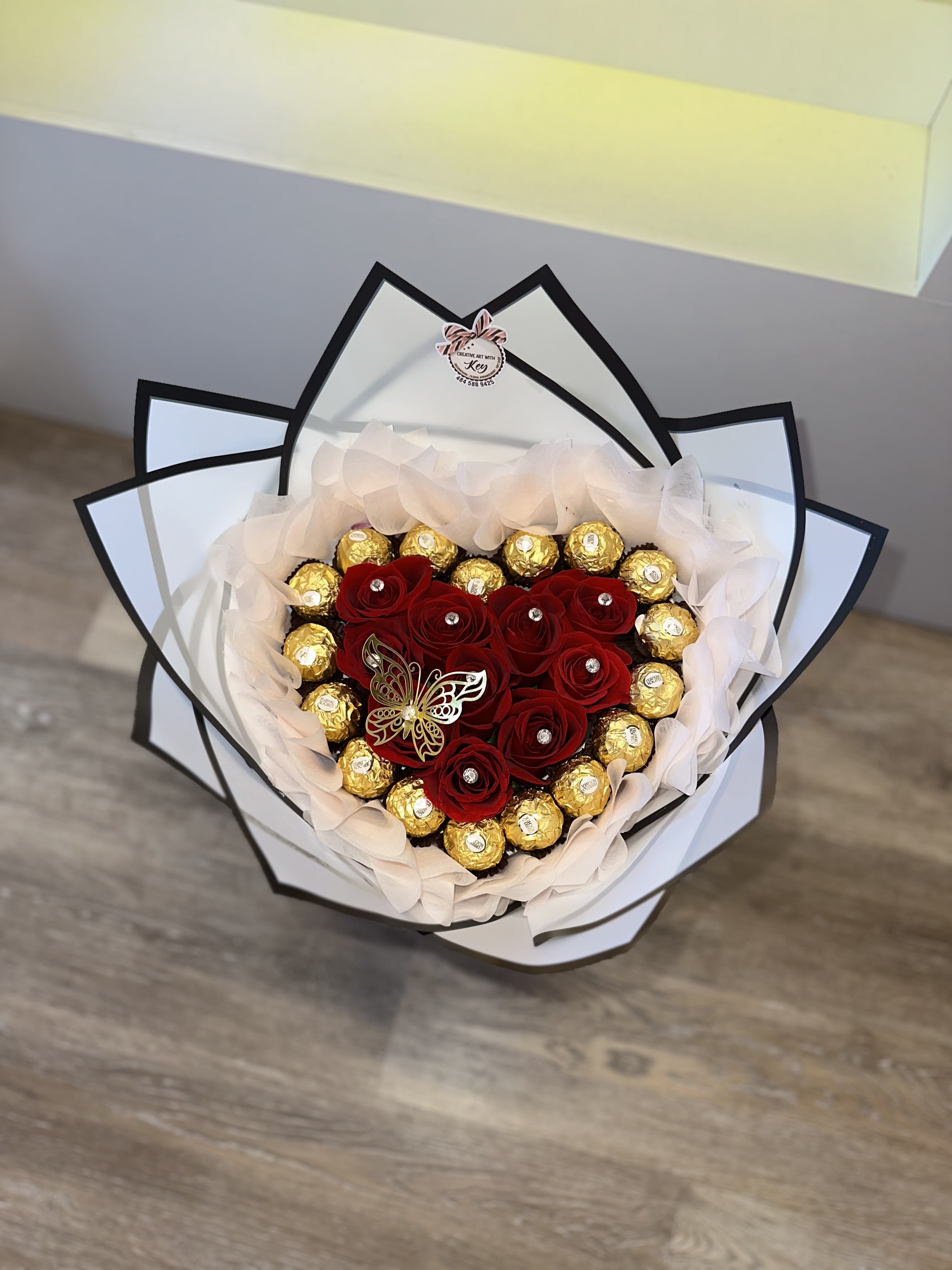 Heart-shaped bouquet of red roses and gold chocolates wrapped in white paper