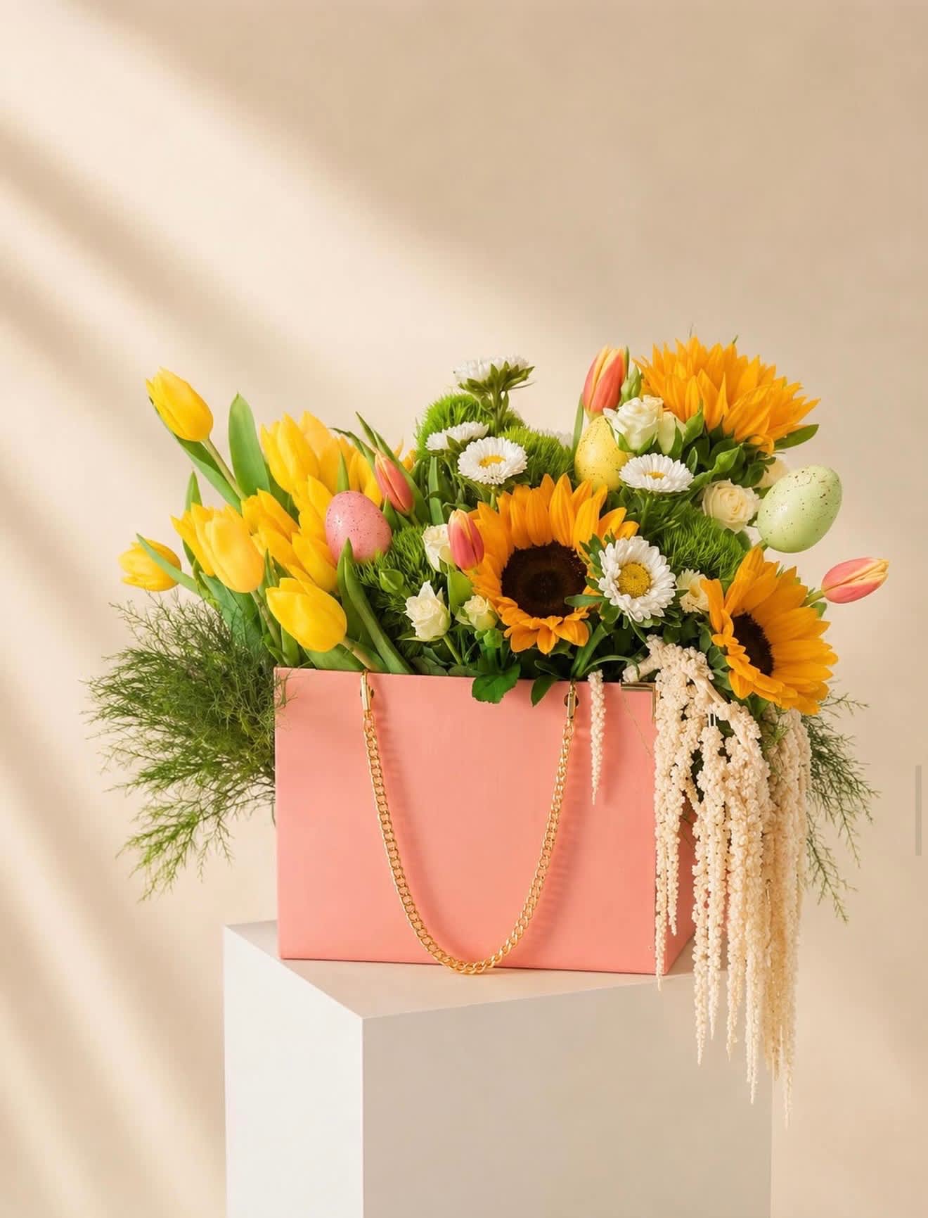 Pink gift bag filled with yellow tulips, sunflowers, and daisies