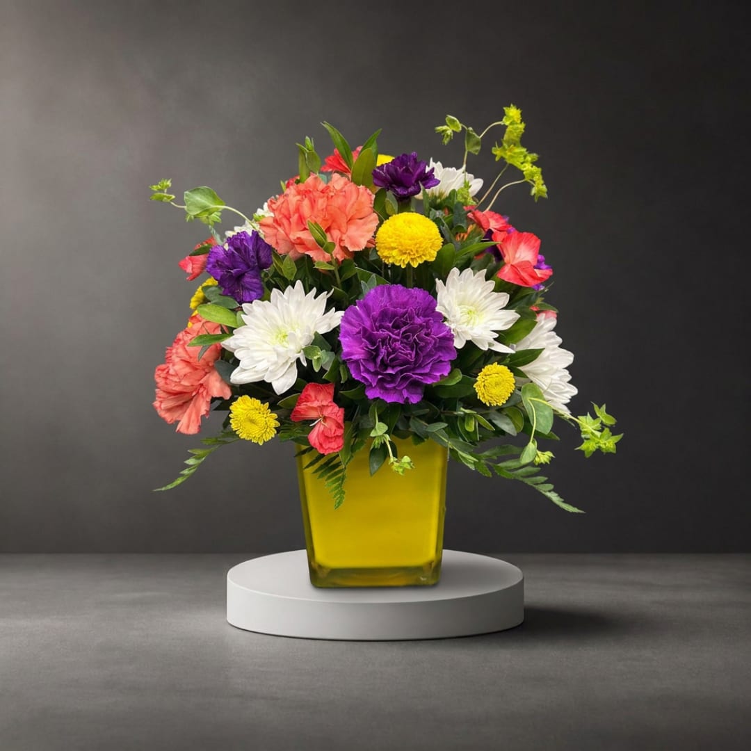 Colorful mixed flower arrangement in a yellow glass vase