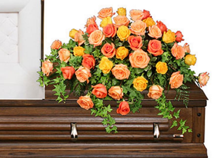 Orange and yellow roses arranged on a wooden casket