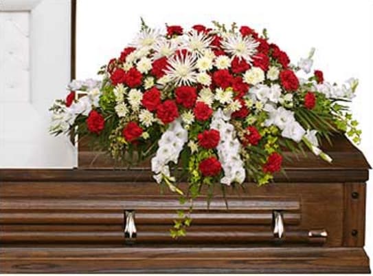 Red and white funeral spray on a wooden casket