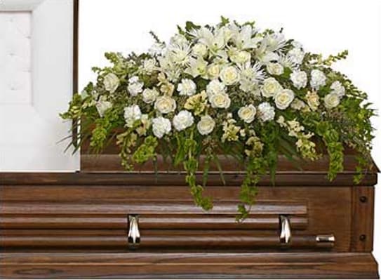 White floral casket spray on a wooden casket