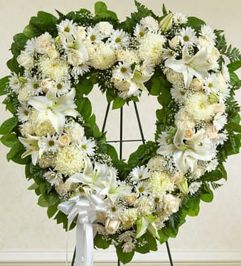 Heart-shaped white floral wreath on a stand with a white ribbon