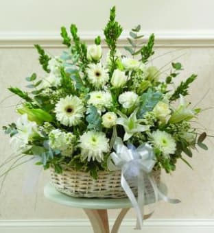 White floral basket arrangement with a ribbon bow