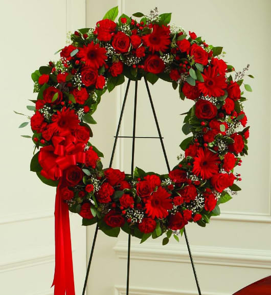 Red floral wreath on a black stand with a red ribbon