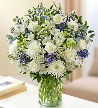 White and blue mixed bouquet in a clear glass vase