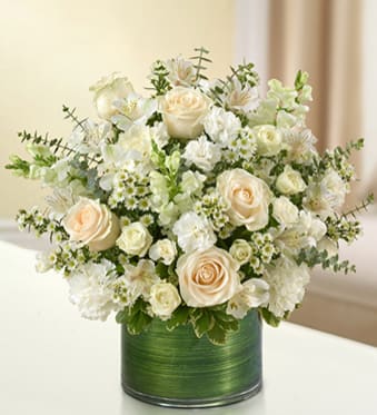 Cream roses and white flowers arranged in a green vase