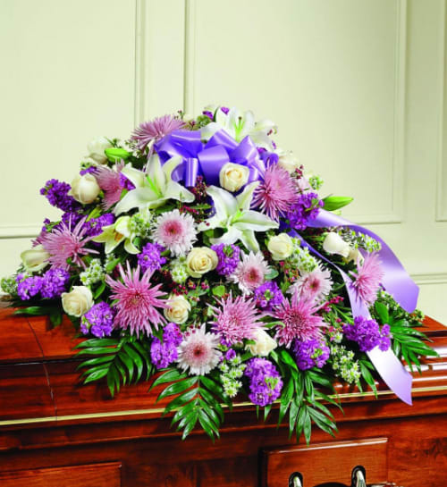 Purple and white floral casket spray with a lavender ribbon
