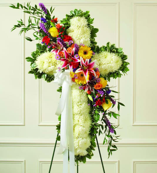 Standing floral cross with white blooms and colorful mixed flowers on an easel