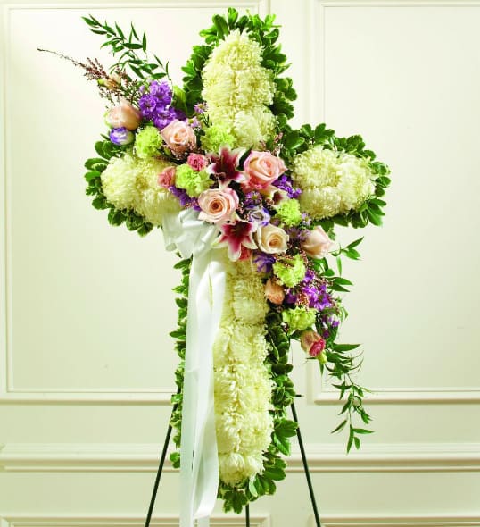 Standing floral cross with white and purple flowers and a white ribbon