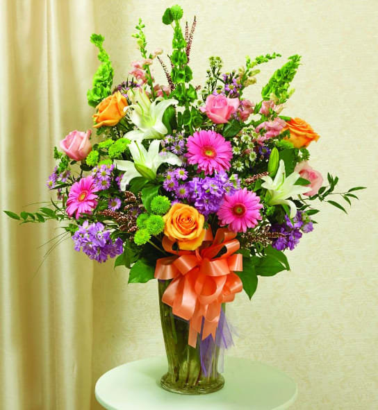 Colorful mixed bouquet in a tall glass vase with a ribbon bow