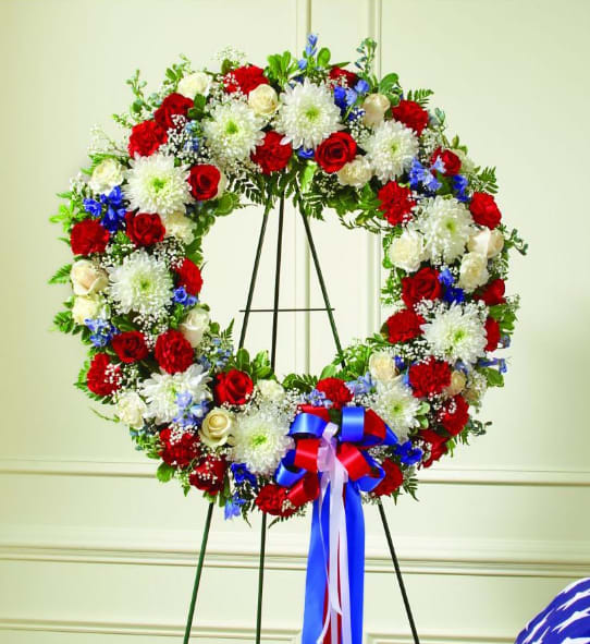 Circular floral wreath of red, white, and blue flowers on an easel